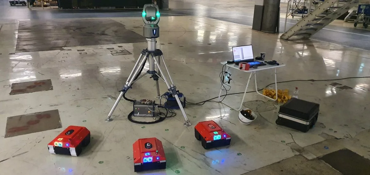 Drei Markierroboter im Einsatz in einer Halle, geführt von einem Lasertracker